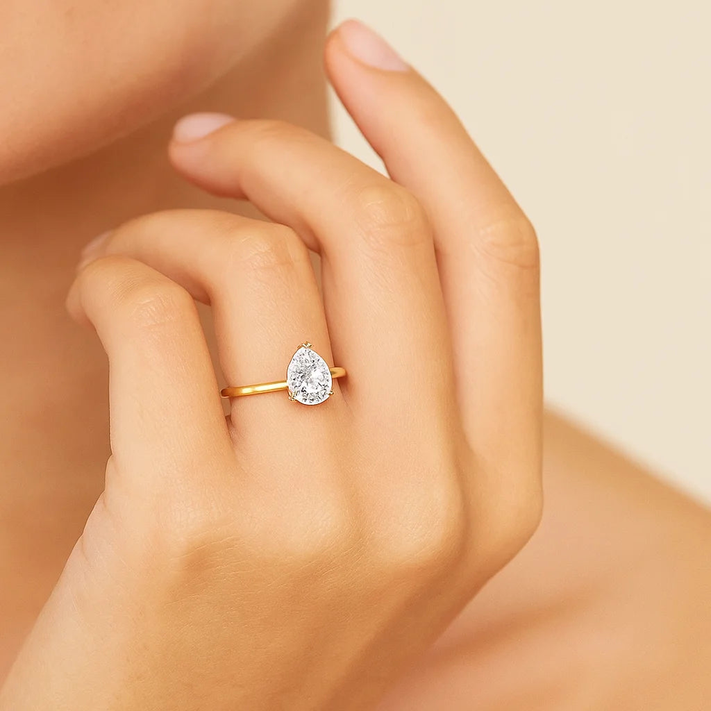 Gold plated ring with a diamond on a hand against a neutral background