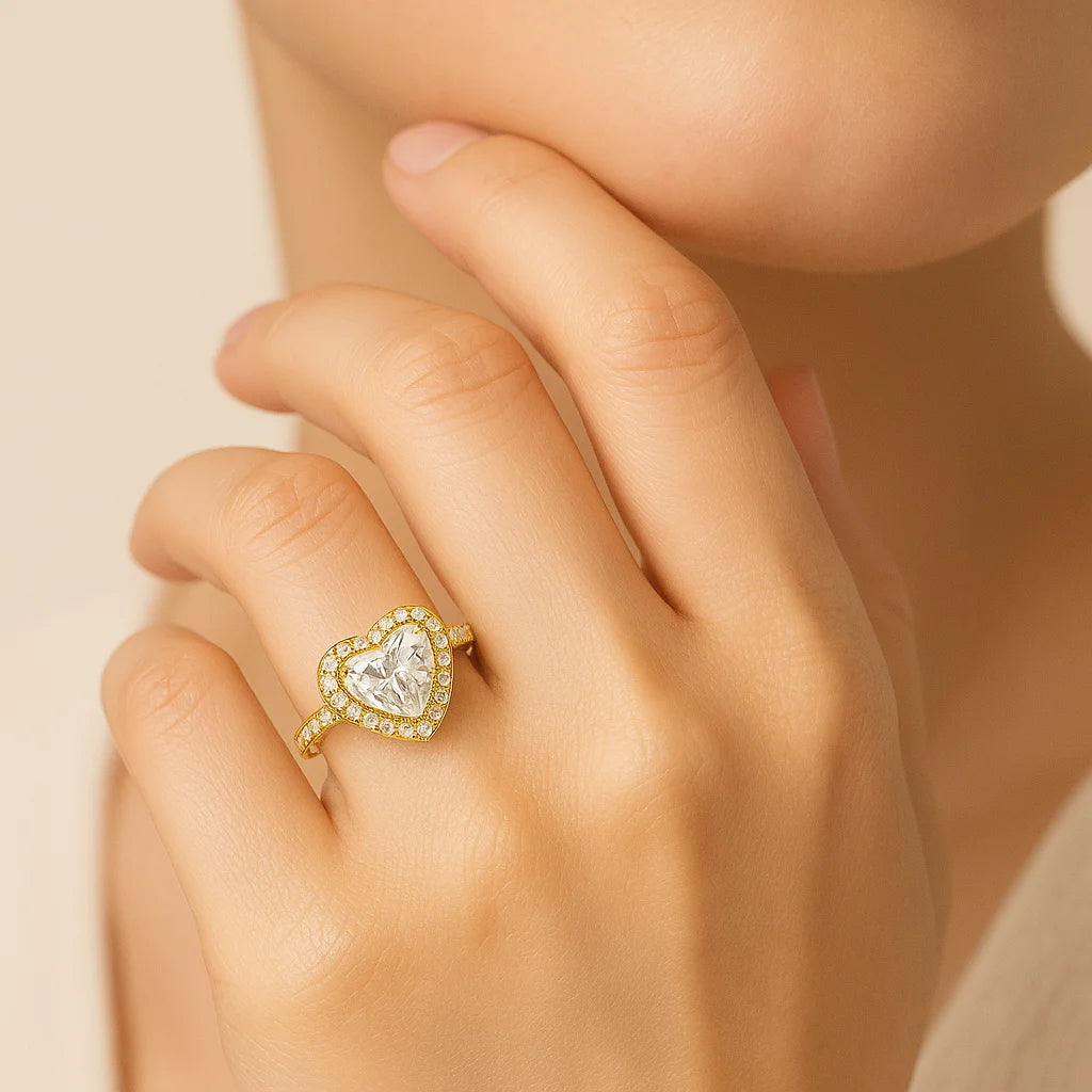 Heart-shaped diamond ring on a hand against a neutral background