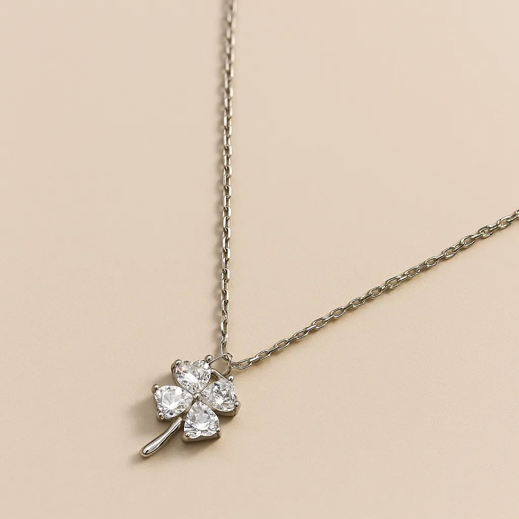 Silver necklace with a clover-shaped pendant on a beige background