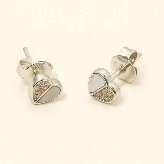 Heart-shaped silver earrings with gemstones on a beige background