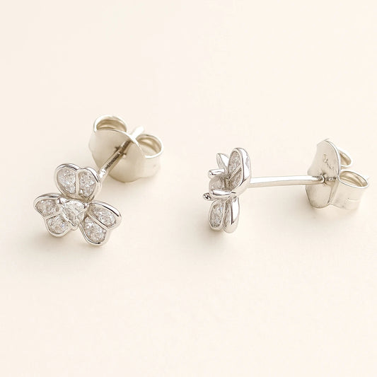 Pair of silver butterfly earrings with clear gemstones on a light beige background