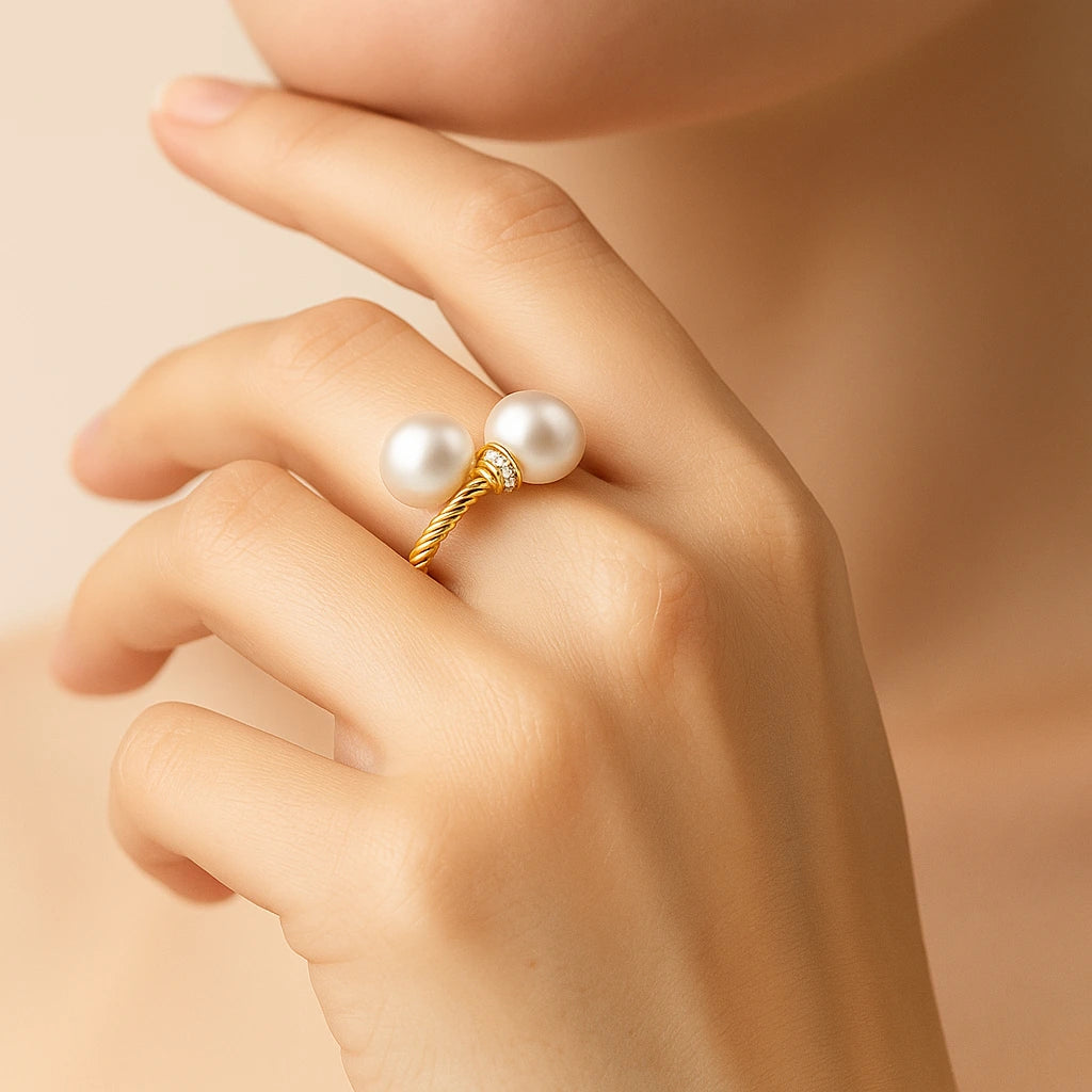 Gold ring with pearls on a hand against a beige background