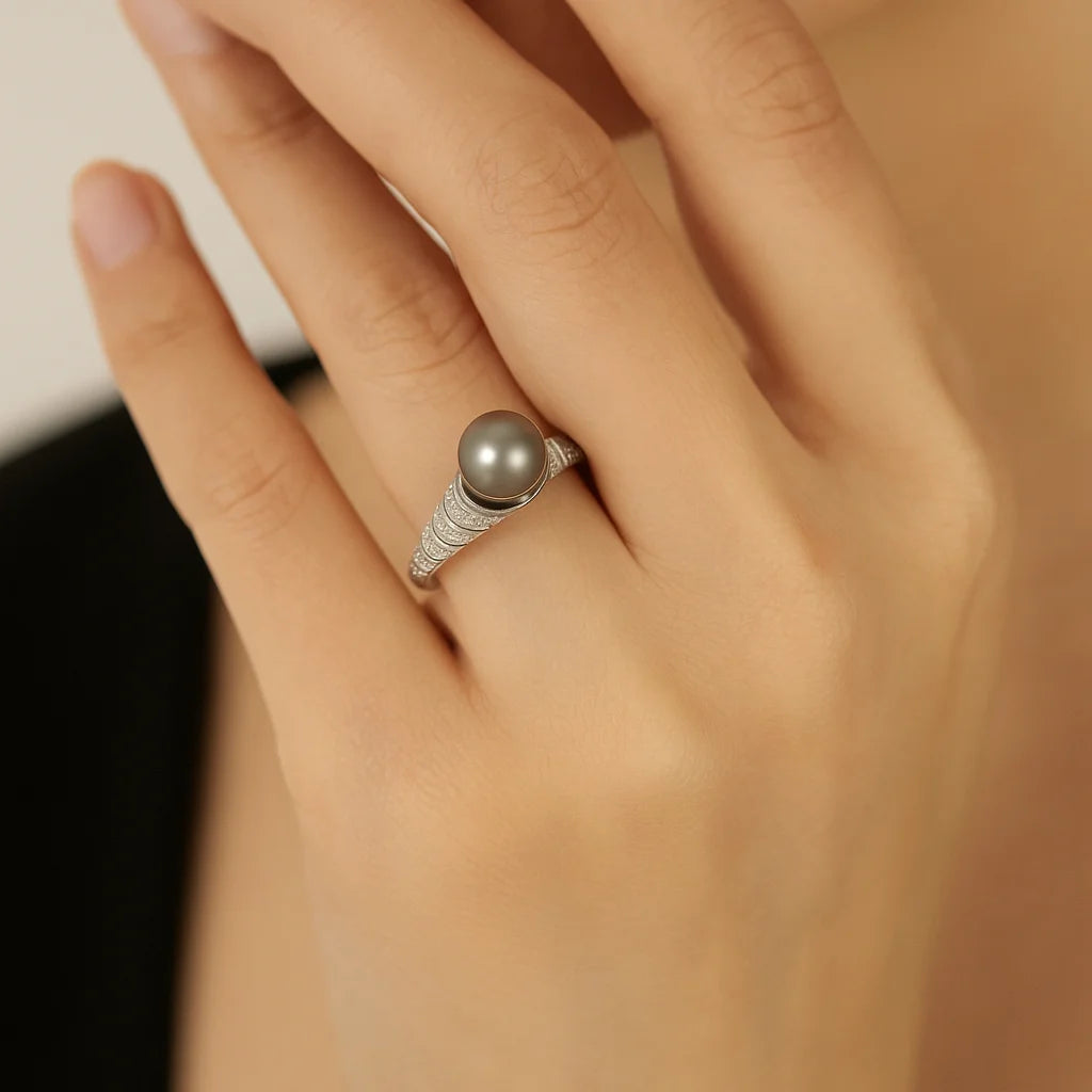 Hand wearing a ring with a pearl on a neutral background