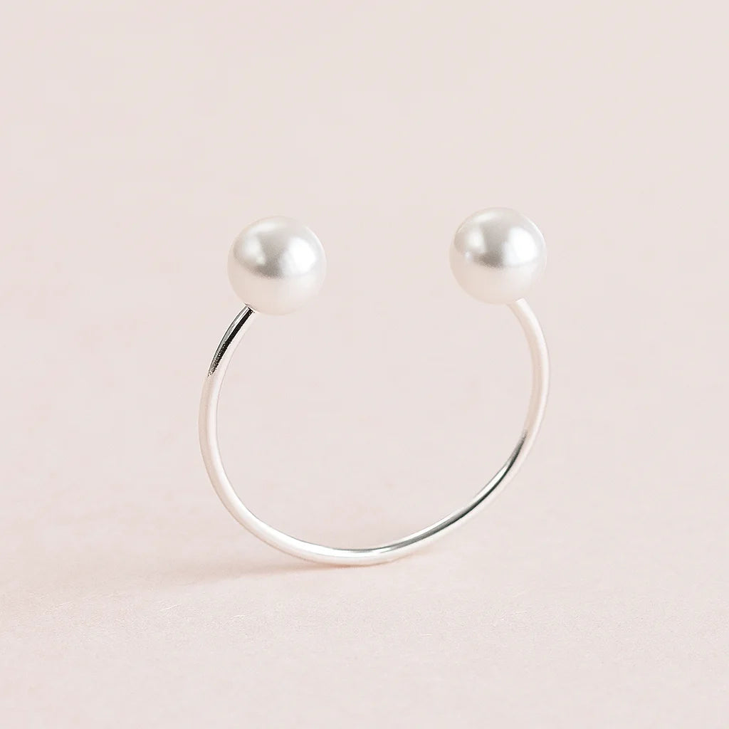 Silver ring with two pearls on a light pink background