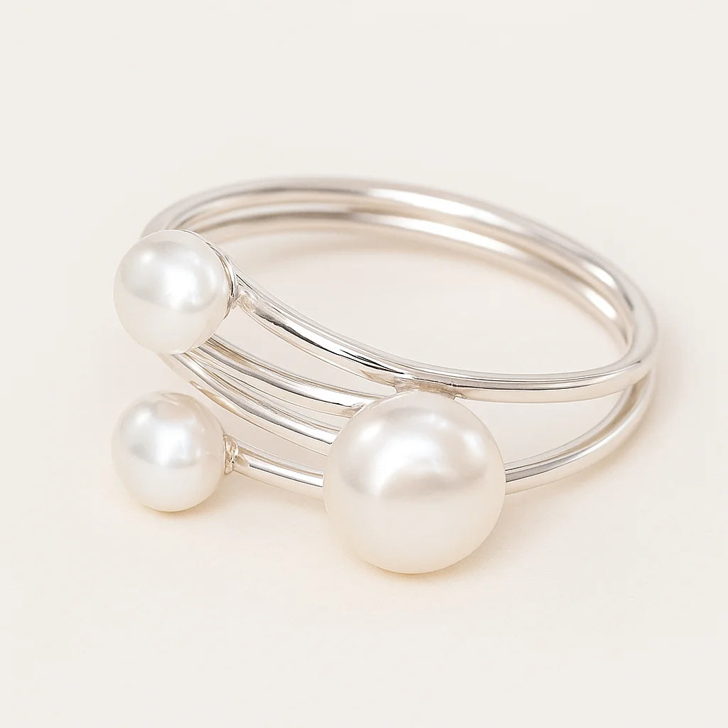 Silver bangle with three pearls on a light background