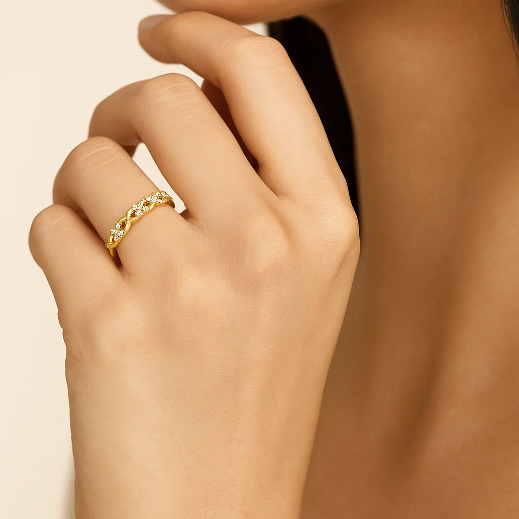 Close-up of a hand wearing a golden ring with small diamonds on a beige background