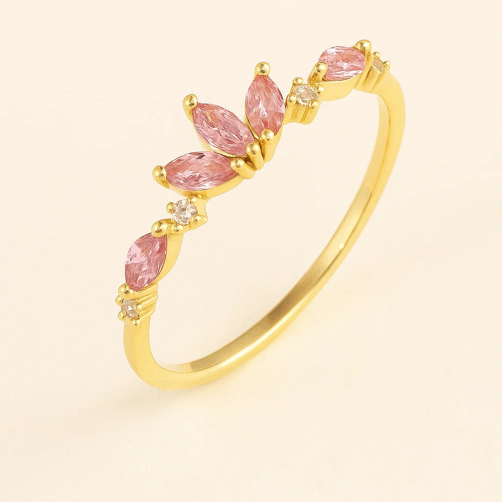 Golden bangle with pink gemstones on a light beige background