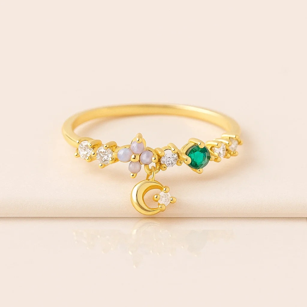Golden ring with green gemstone and moon design on a beige background