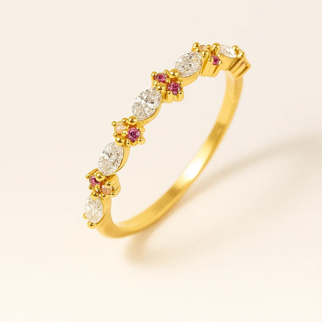Golden ring with diamonds and pink gemstones on a beige background