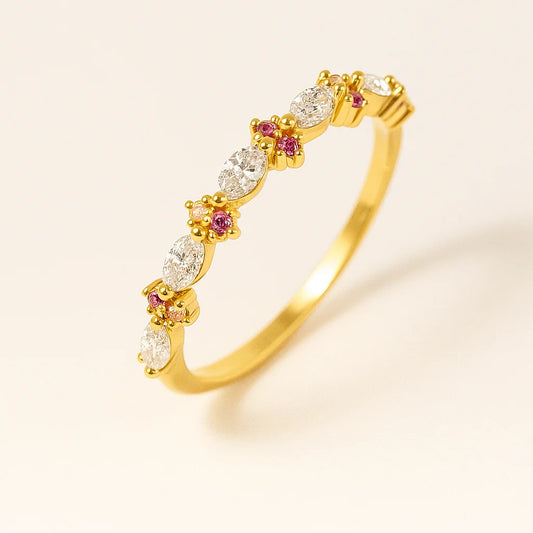 Golden ring with diamonds and pink gemstones on a beige background