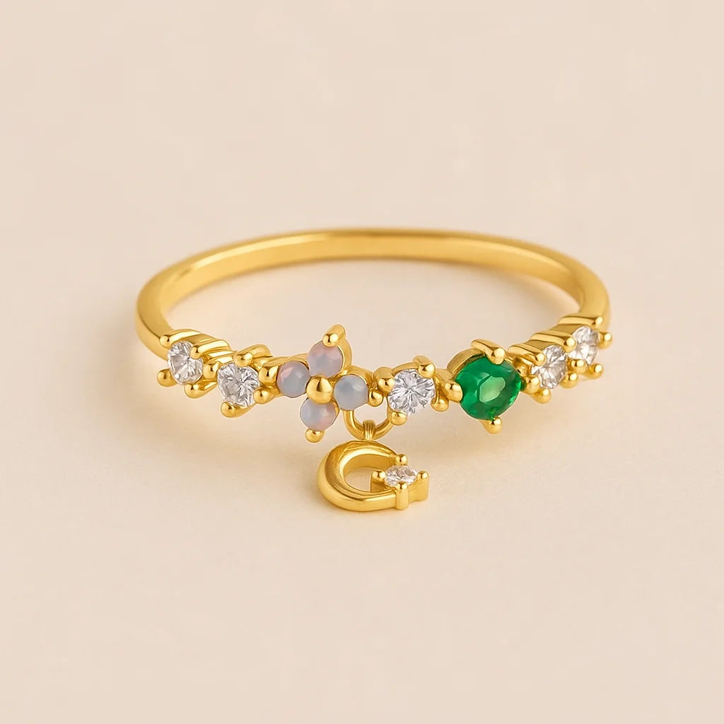 Golden ring with green gemstone and small diamonds on a beige background