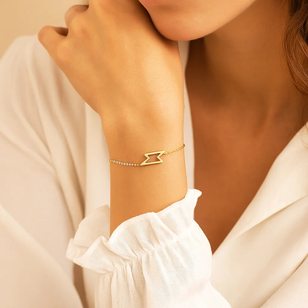 Golden bracelet on a person's wrist with a neutral background