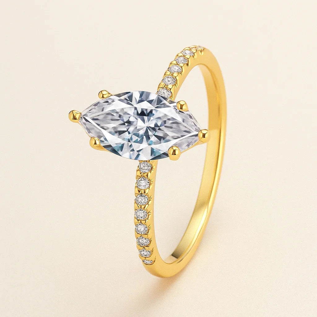 Gold ring with a large central gemstone and smaller stones on a beige background