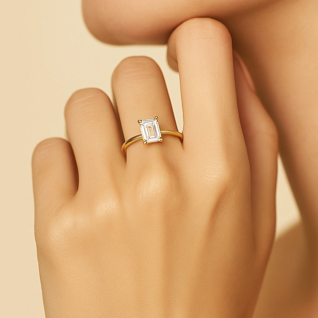 Gold plated ring with a diamond on a hand against a beige background