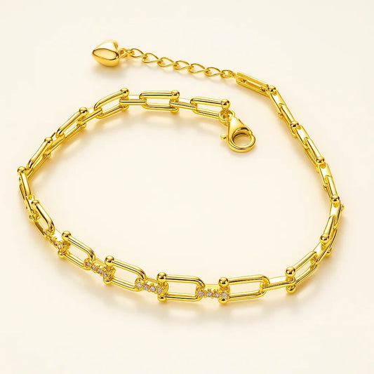A gold-plated 925 sterling silver paperclip link bracelet with pave-set cubic zirconia stones on the center links and a heart charm on the extender.
