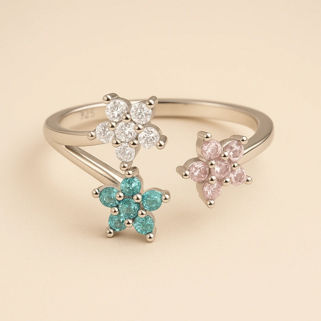 three floral-shaped rings with gemstones on a beige background