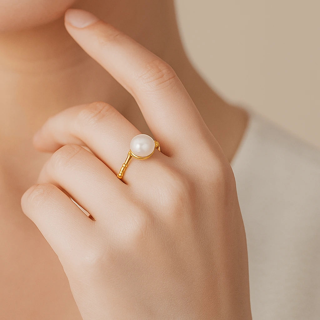 Gold ring with a pearl on a hand against a neutral background
