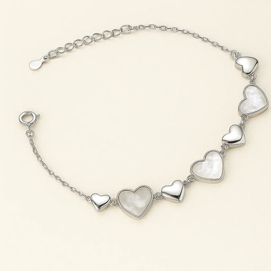 A beautiful gold-plated sterling silver bracelet with a series of polished and mother-of-pearl inlaid heart charms.