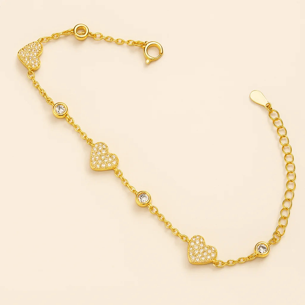 A beautiful gold-plated sterling silver bracelet featuring multiple pavé heart charms and single cubic zirconia accents.