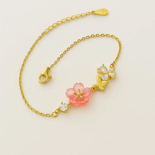 A gold-plated 925 sterling silver bracelet with a pink floral charm and a butterfly, accented with clear cubic zirconia stones.
