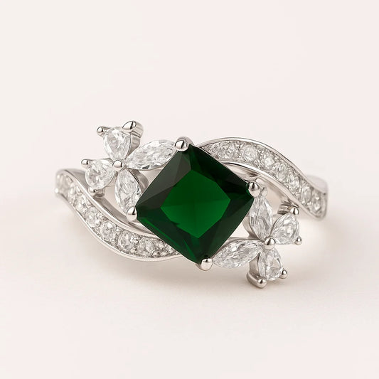 A 925 sterling silver ring with a central square green stone and a twisting band with floral clusters and pavé cubic zirconia.
