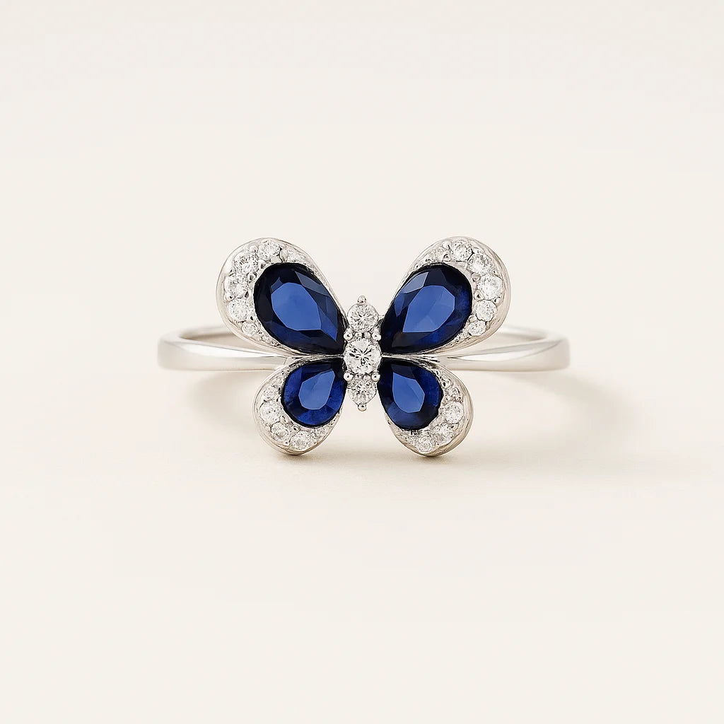 A 925 sterling silver ring with a butterfly centerpiece, with wings of blue or green pear-cut stones and a halo of pavé cubic zirconia.