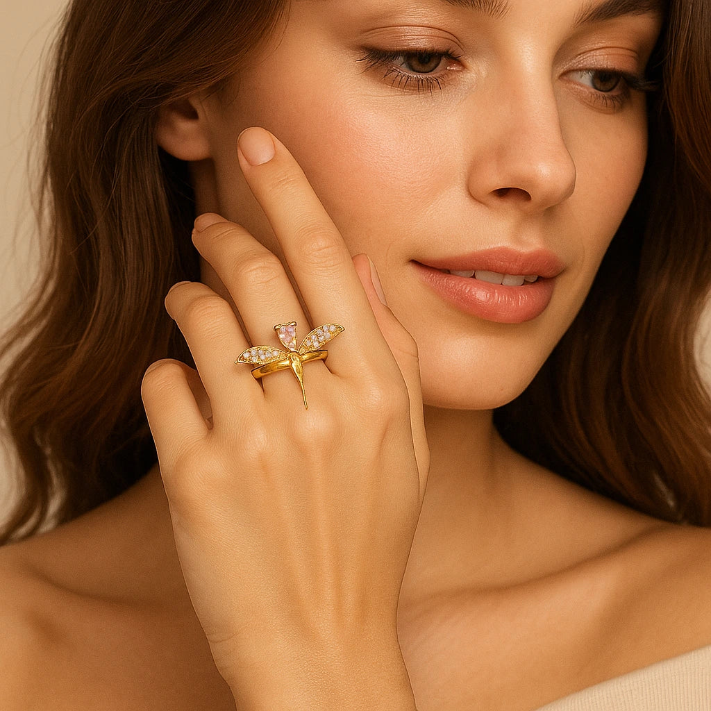 Woman wearing a gold ring with a butterfly design on her finger, against a neutral background
